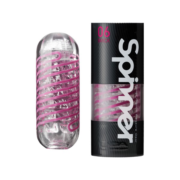 “투명 실리콘으로 제작된 텐가 스피너 브릭 자위기구와 검정색 원통형 패키지. 제품 본체는 내부가 보이며 분홍색 스파이럴 구조가 감겨 있고, 패키지에는 ‘Spinner 06 Brick’이라는 모델명이 표시됨. 남성 자위기구 입문자에게 추천되는 텐가 스피너 시리즈 제품.”